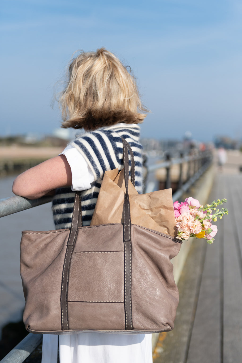 A lady looking out to sea wearing a soft Italian leather tote bag taupe colour made in Italy UK independent label 