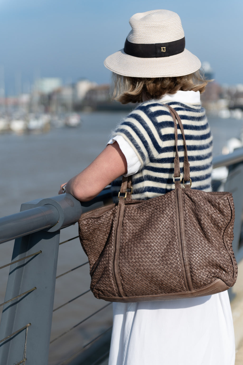A lady wearing a taupe hand woven Italian leather tote bag looking out to sea made in Florence Italy Independent label Sussex Surrey Kent Yorkshire Cotswolds 