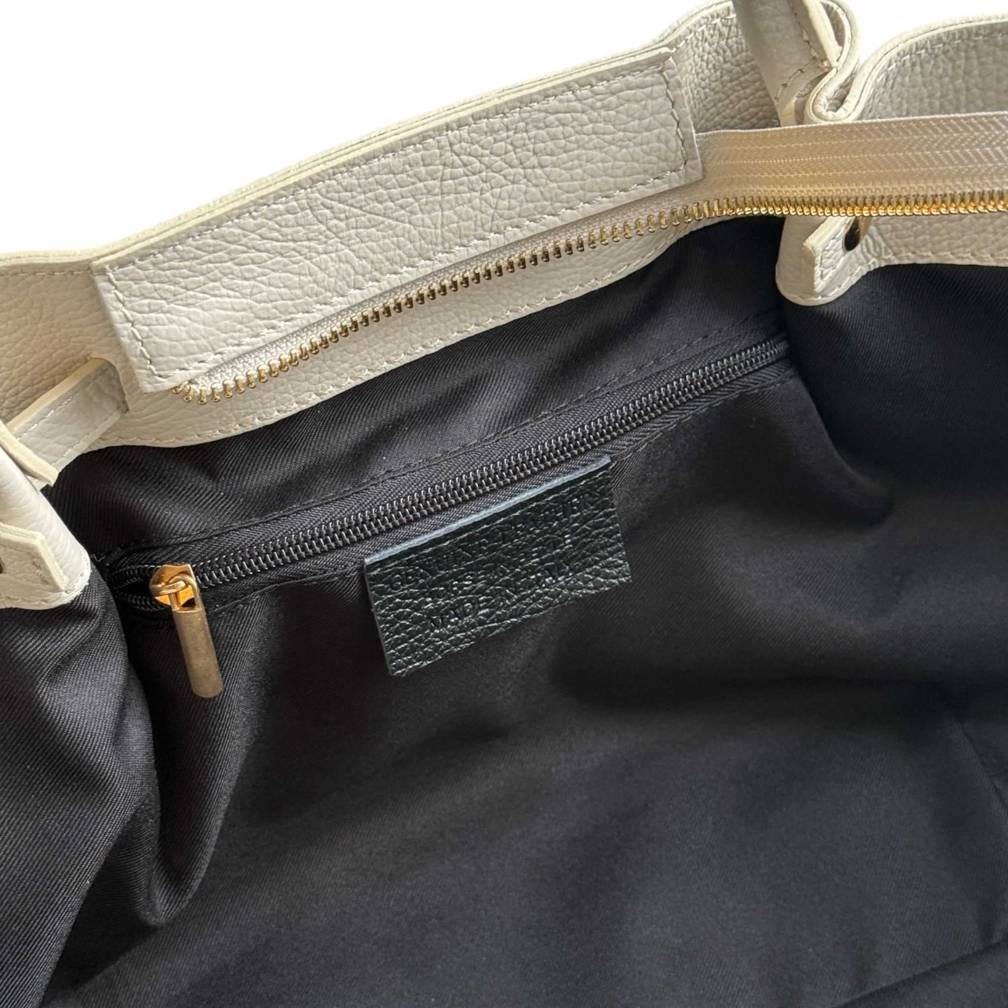 Showing the inside zip of a cream handbag