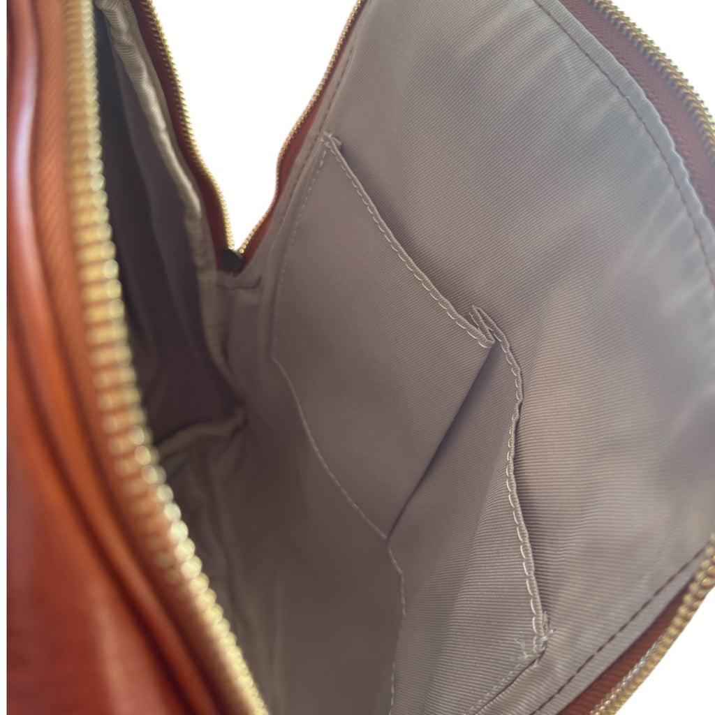 Close-up of a Tan Italian leather backpack bag with a zipper, showing the interior lining.