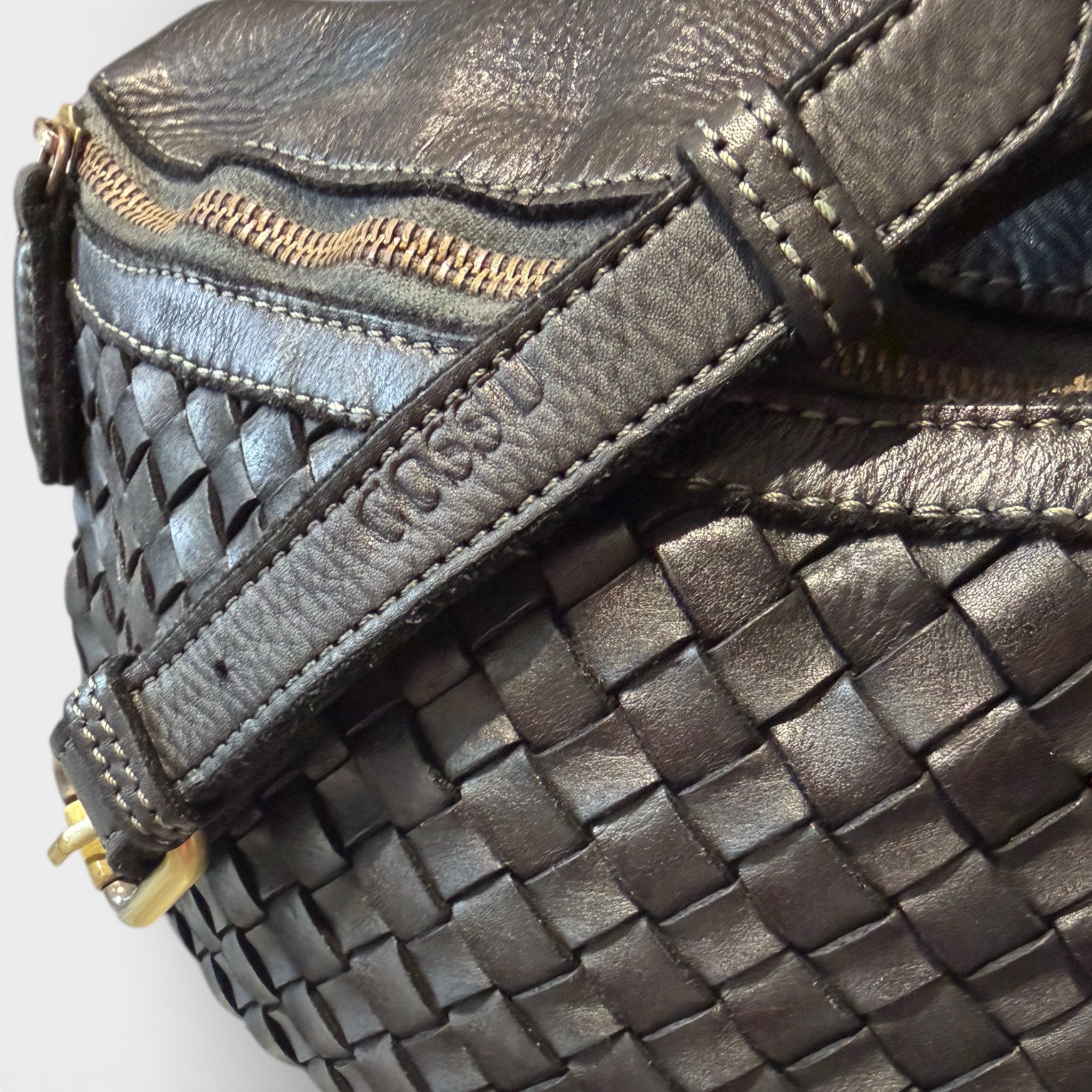 Close up of black woven Italian leather cross body bag showing the logo Cossu 