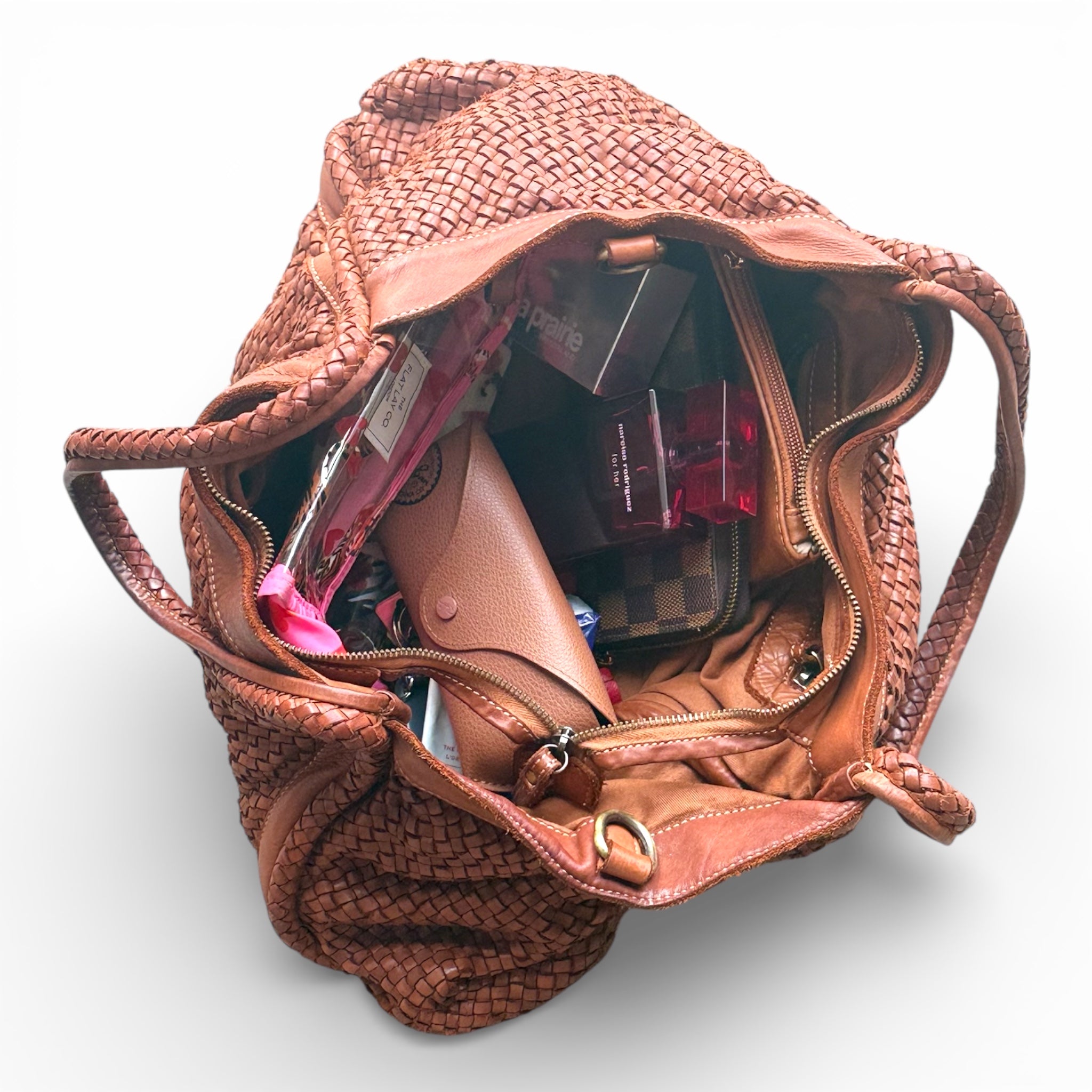 Tan woven Italian leather handbag with makeup items on a white background. Kent Surrey Sussex Independent retailer 