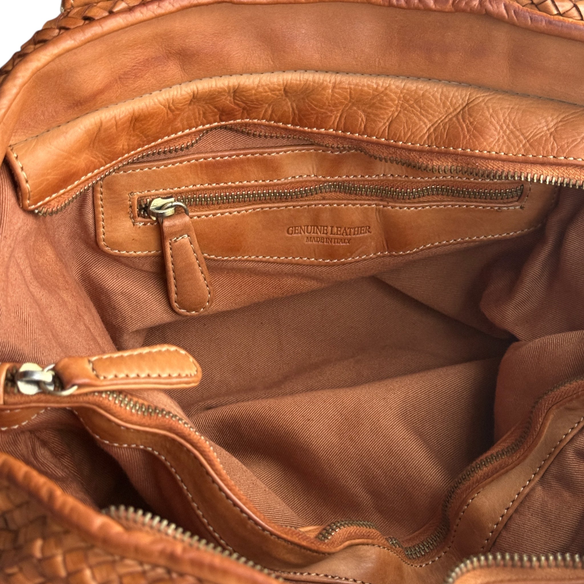 Close-up of a tan Italian leather bag with visible stitching and 'Genuine Leather' label. Cossu U.K. Independent label 